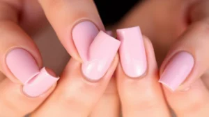 Close-up of elegantly manicured hands with soft baby pink nail polish, natural lighting, showing glossy finish on natural nail beds, professional and polished appearance
