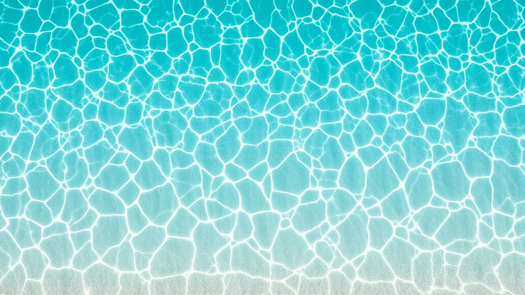 Overhead view of crystal-clear turquoise shallow water with white sand ripples visible beneath, gentle waves at shoreline, tropical beach setting